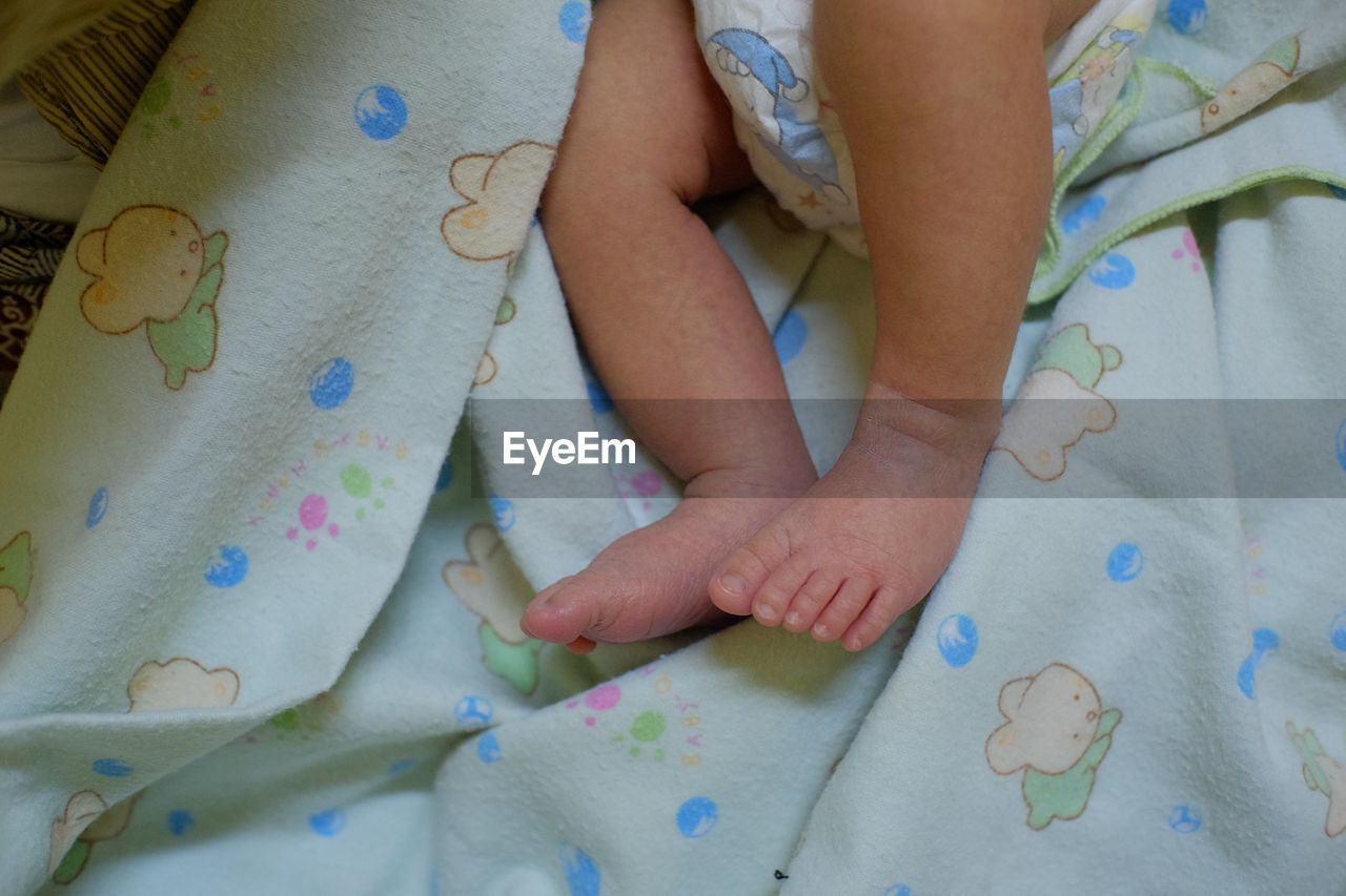 child, childhood, one person, indoors, bed, human leg, hand, high angle view, person, toddler, blue, furniture, women, lifestyles, textile, baby, relaxation, close-up, female, skin, innocence, bedroom, midsection, limb, linen, art, clothing