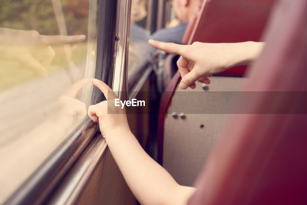 Cropped image of family pointing through bus window