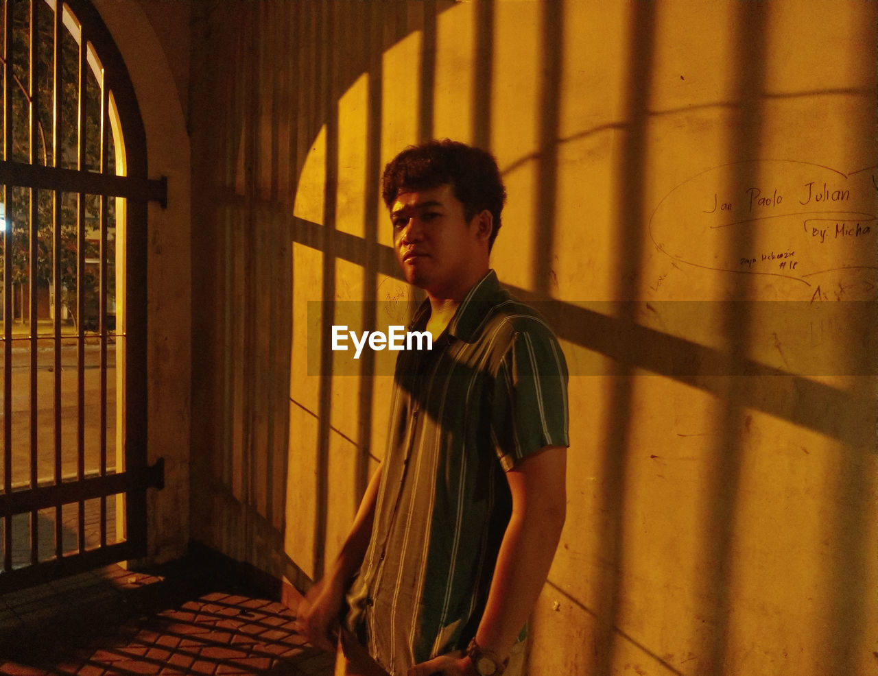 Portrait of young man standing by wall at night