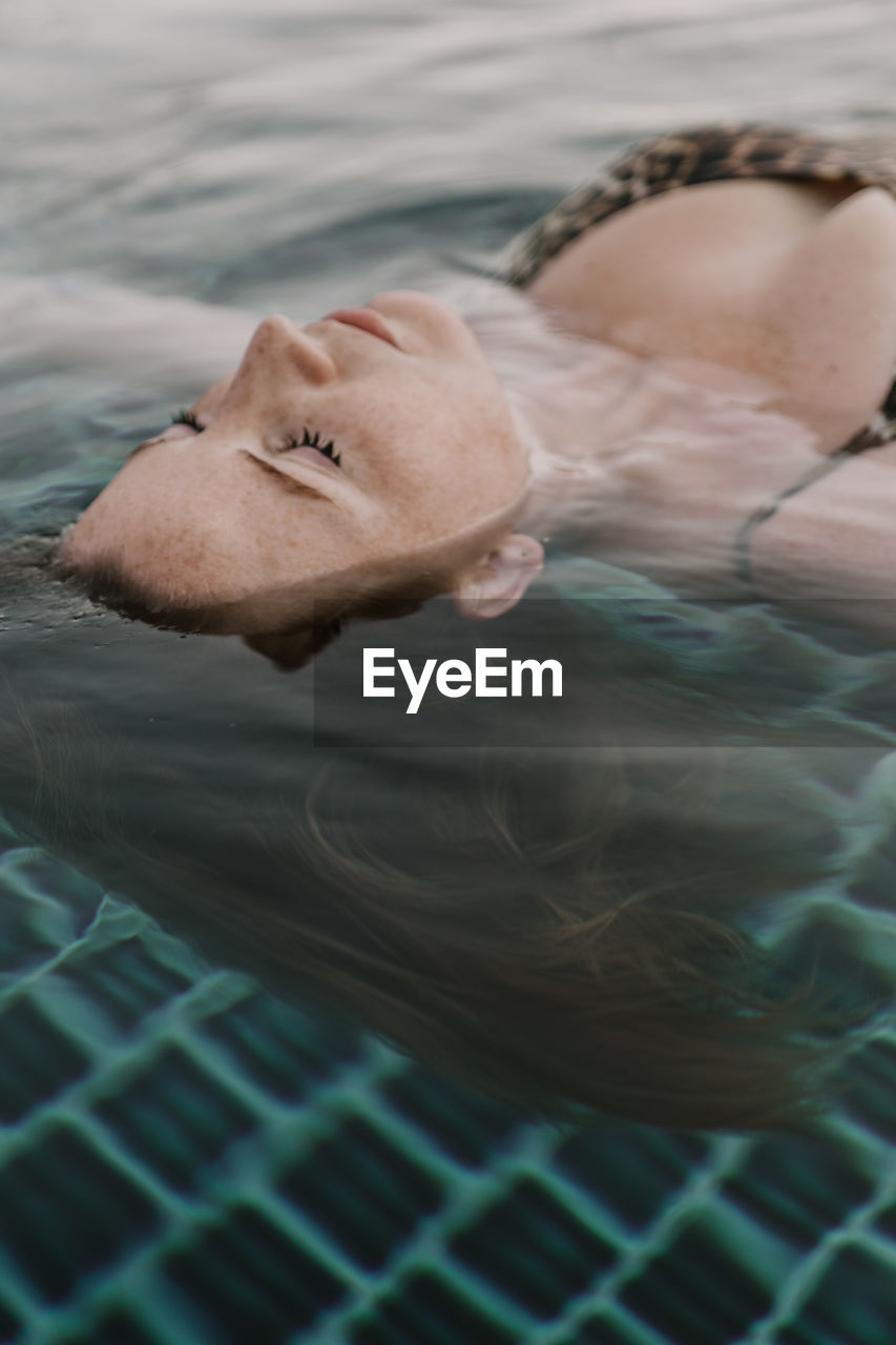 Close-up of woman floating on swimming pool