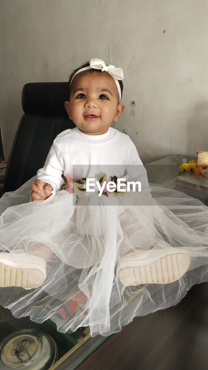 Portrait of cute baby girl sitting at home