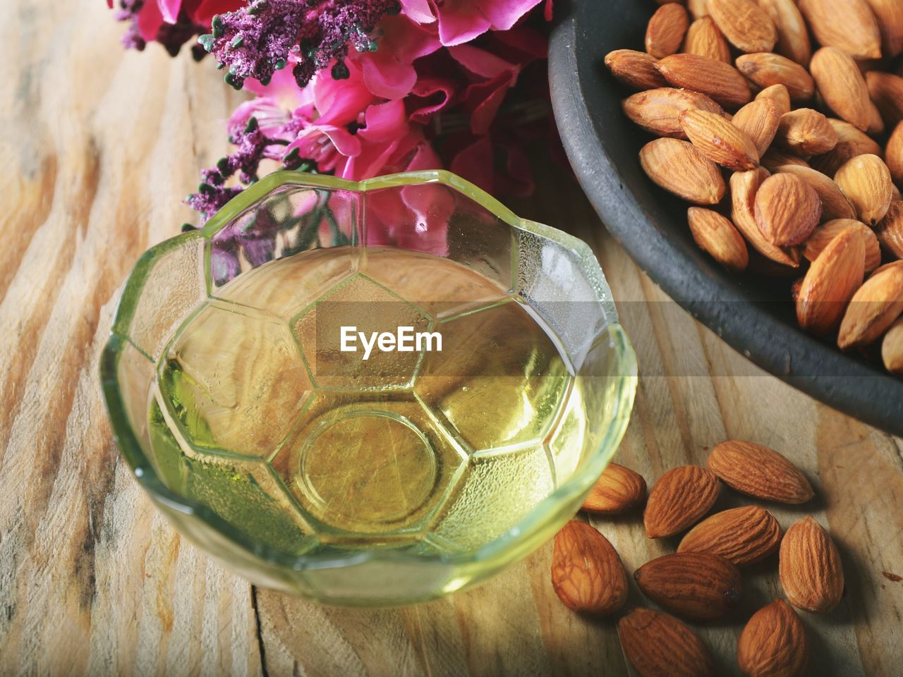 High angle view of almonds and oil in bowl over table