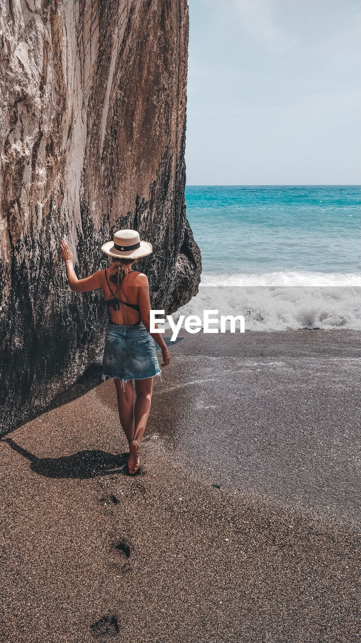 Rear view of woman standing at beach