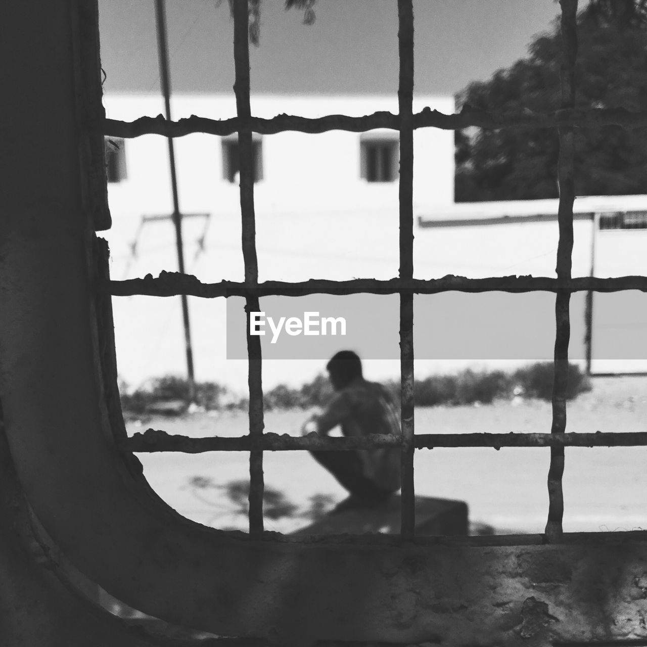 Man crouching on wall seen through window