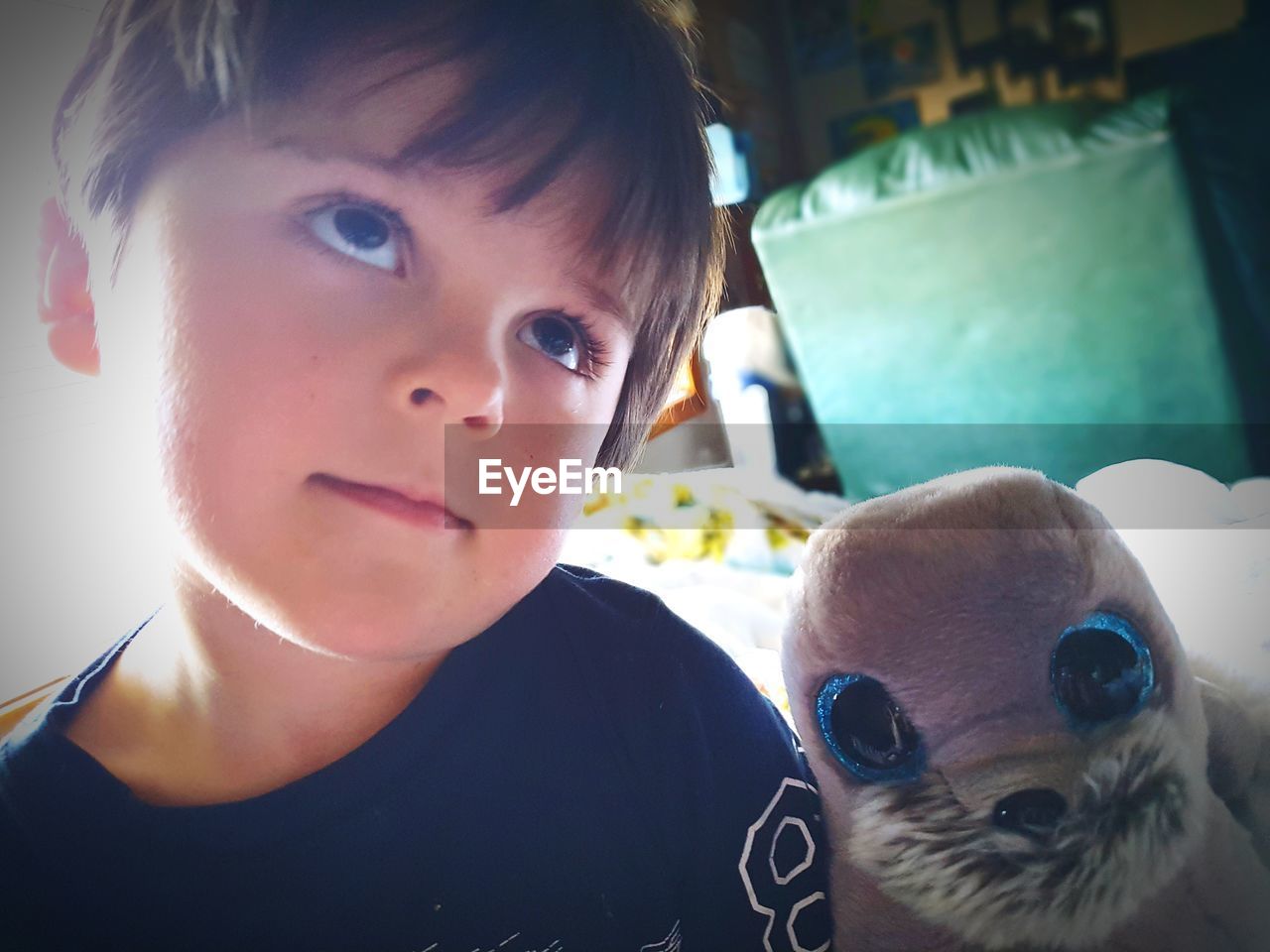 Close-up of cute boy with stuffed toy looking away while sitting at home