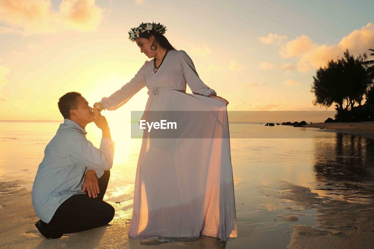 COUPLE KISSING AT BEACH DURING SUNSET