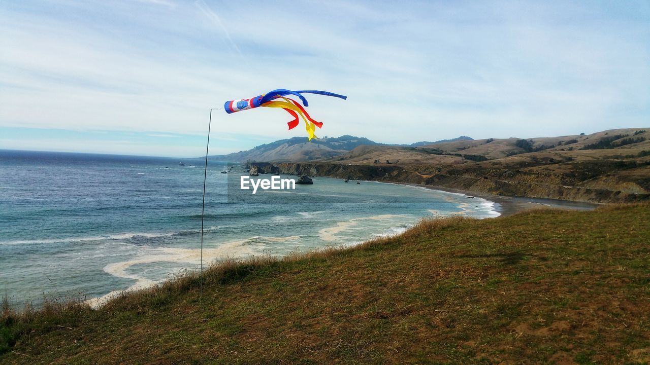 Scenic view from ocean cliff with wind sock against sky