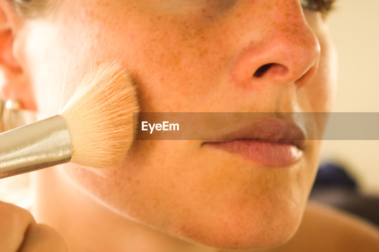 Close-up of woman applying make-up with brush