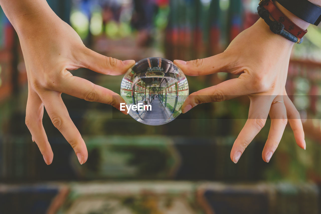 Close-up of hands holding crystal ball with reflection