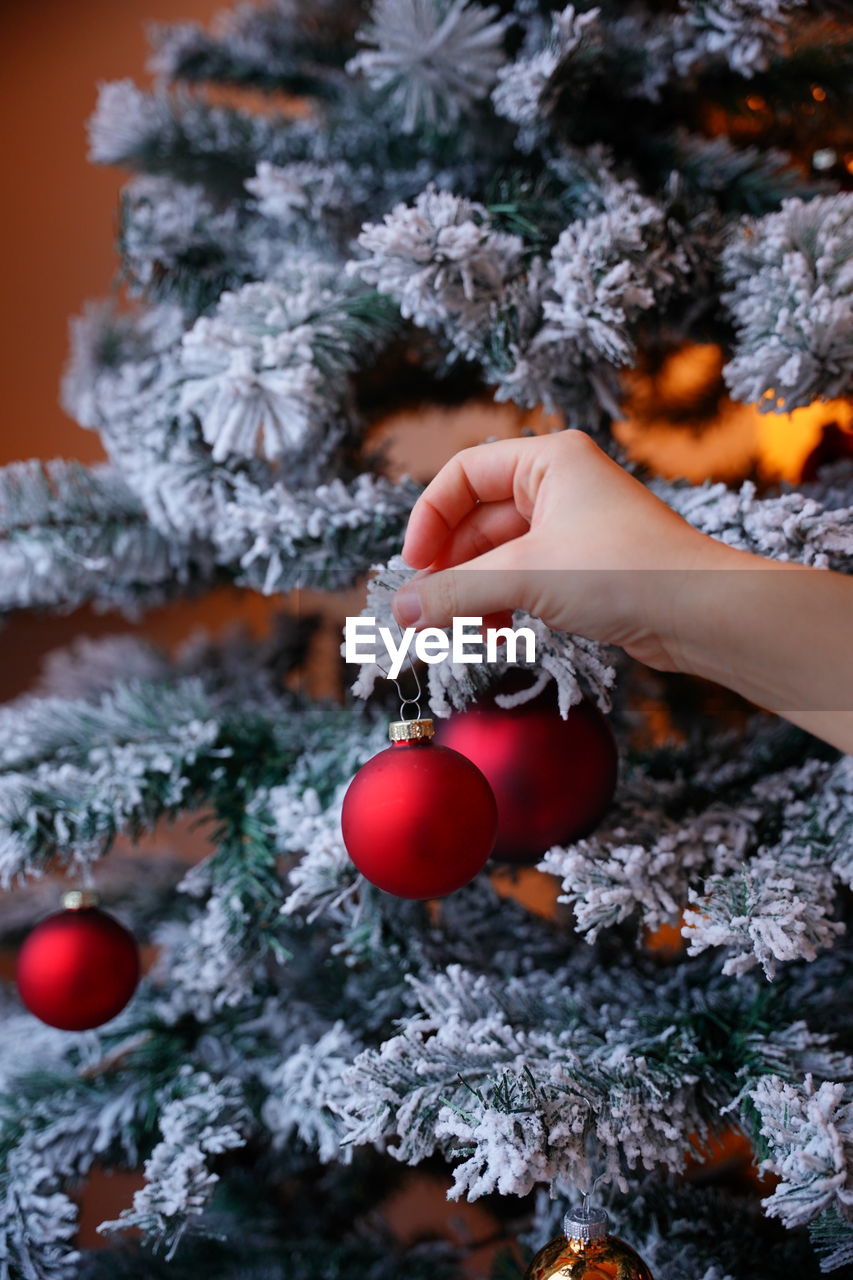 Cropped hand of woman holding christmas decoration on christmas tree