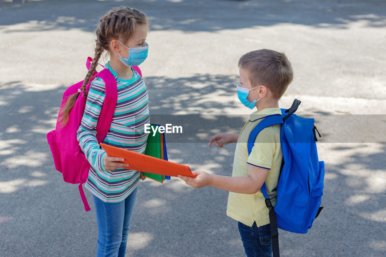 Back to school. brother and sister or boy and girl wearing protective medical masks 