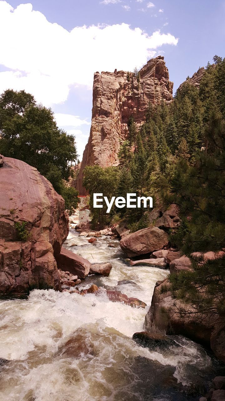 Stream amidst rocky mountains against sky