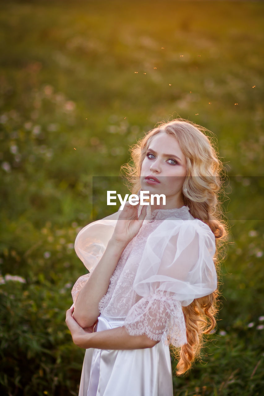 Portrait of young woman standing on field 