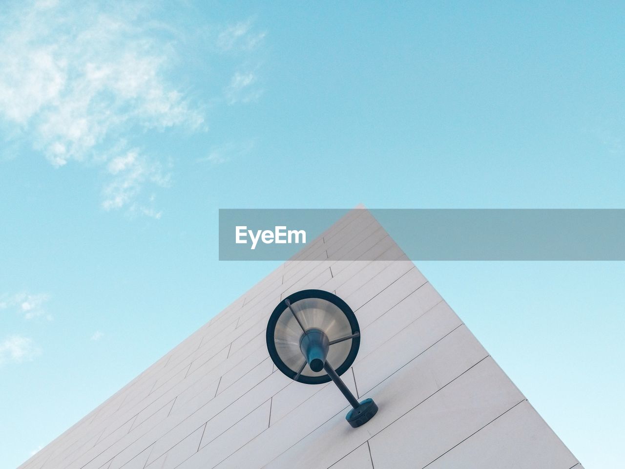 Low angle view of lighting equipment on wall of building against blue sky