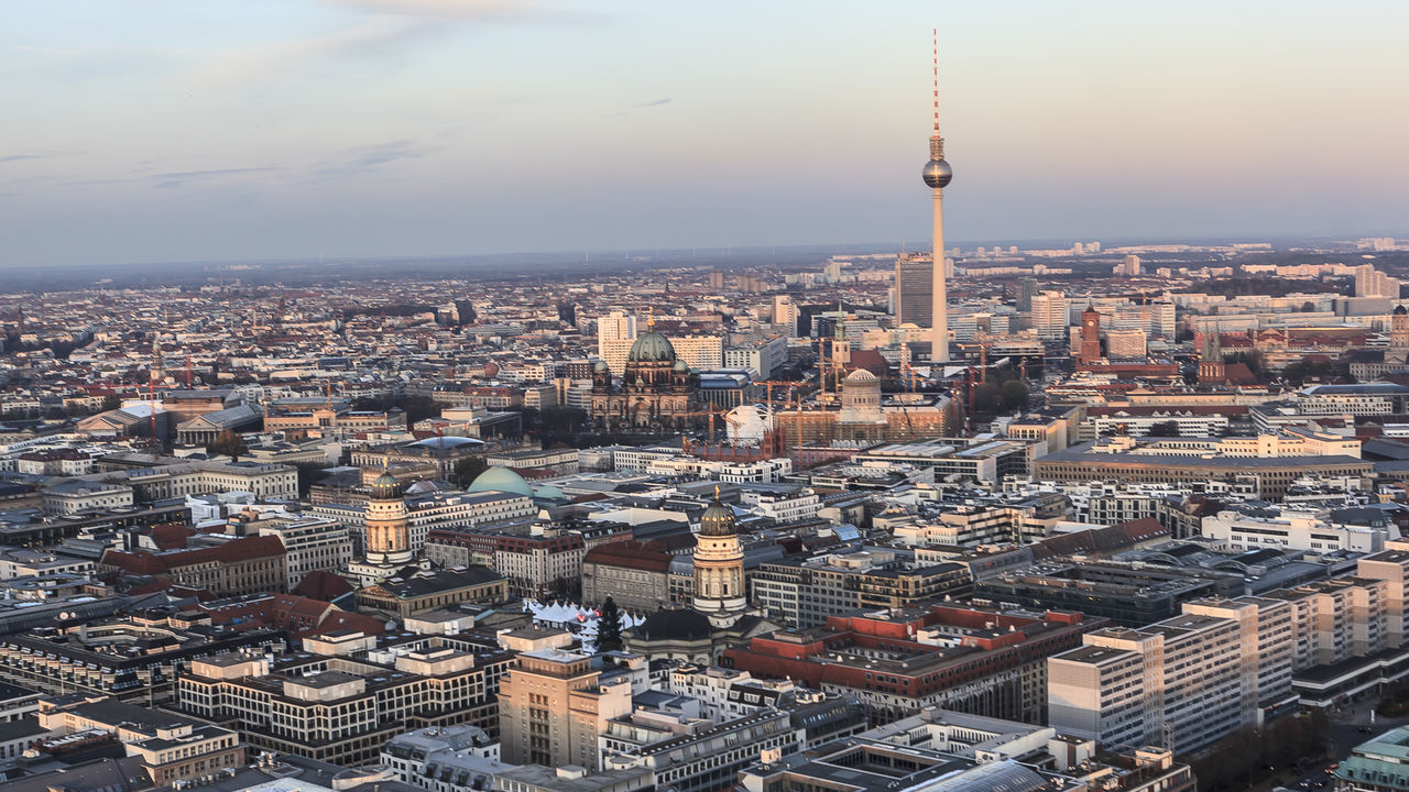 Fernsehturm amidst cityscape against sky during sunset