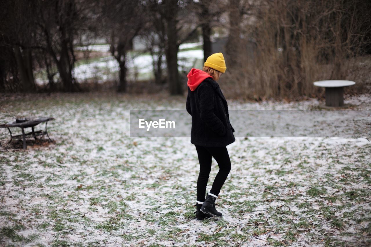 REAR VIEW OF WOMAN WALKING IN SNOW COVERED LAND