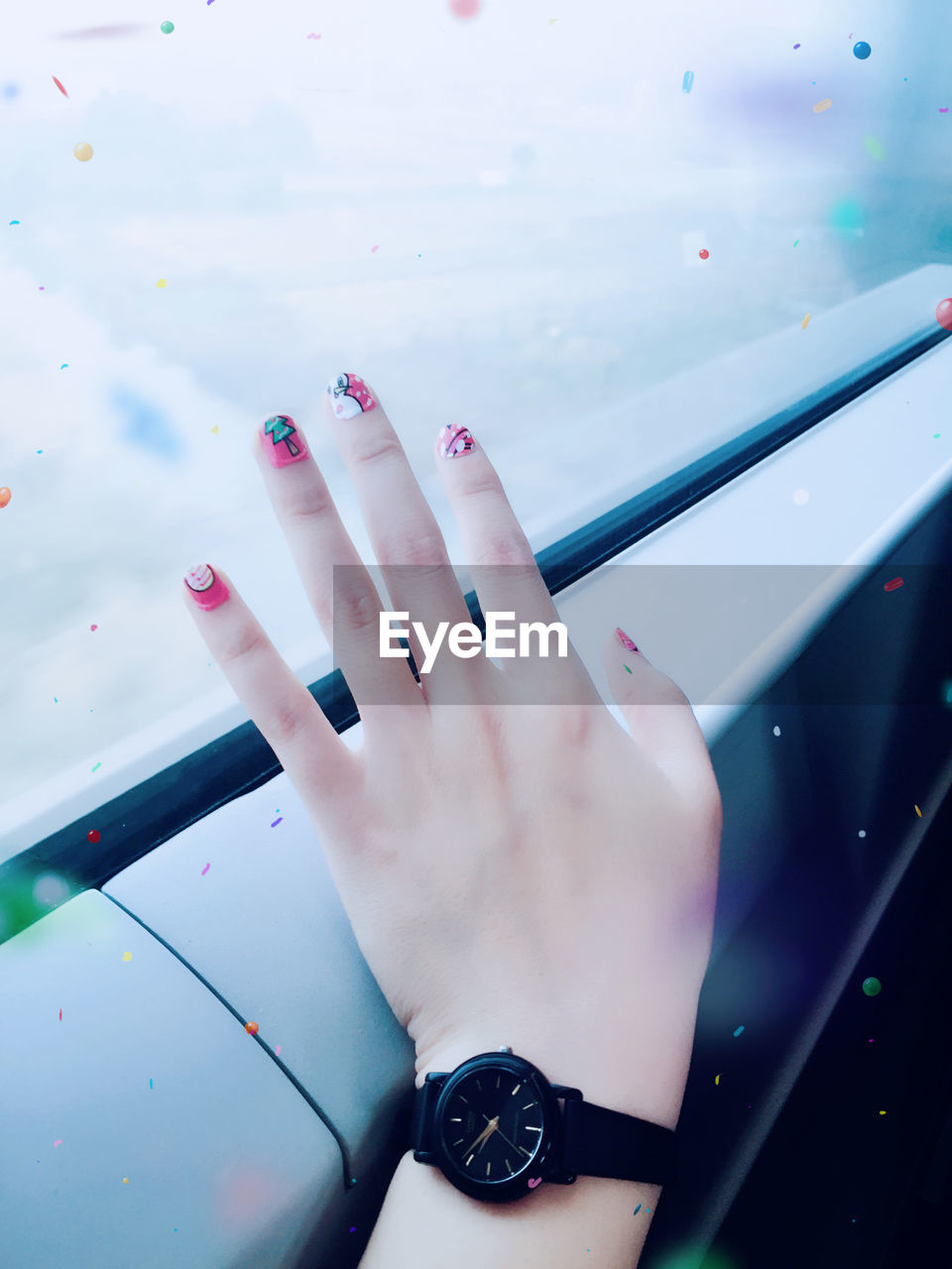 Cropped hand of woman showing nail art by window in train