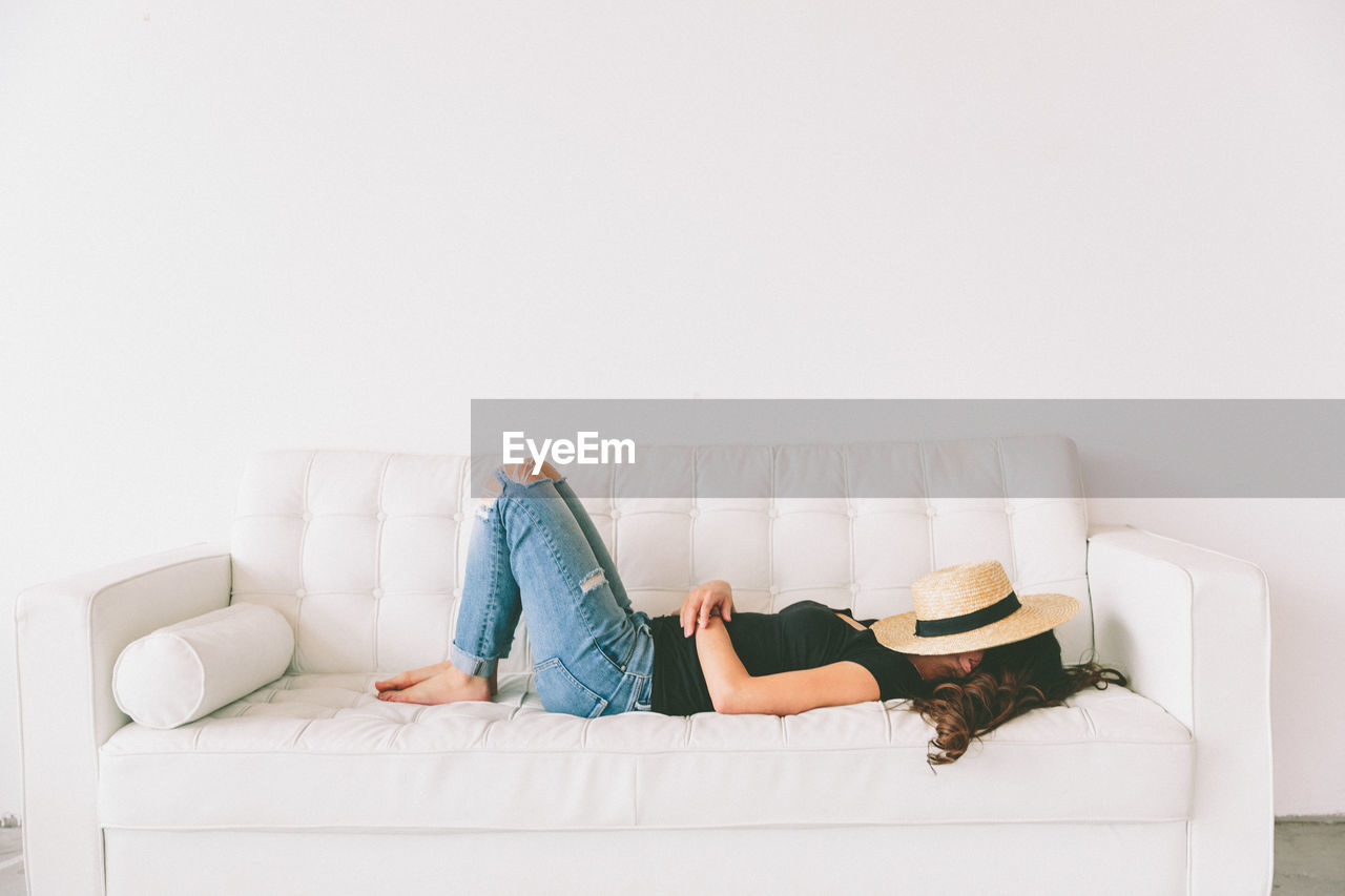 Side view of young woman lying on sofa at home