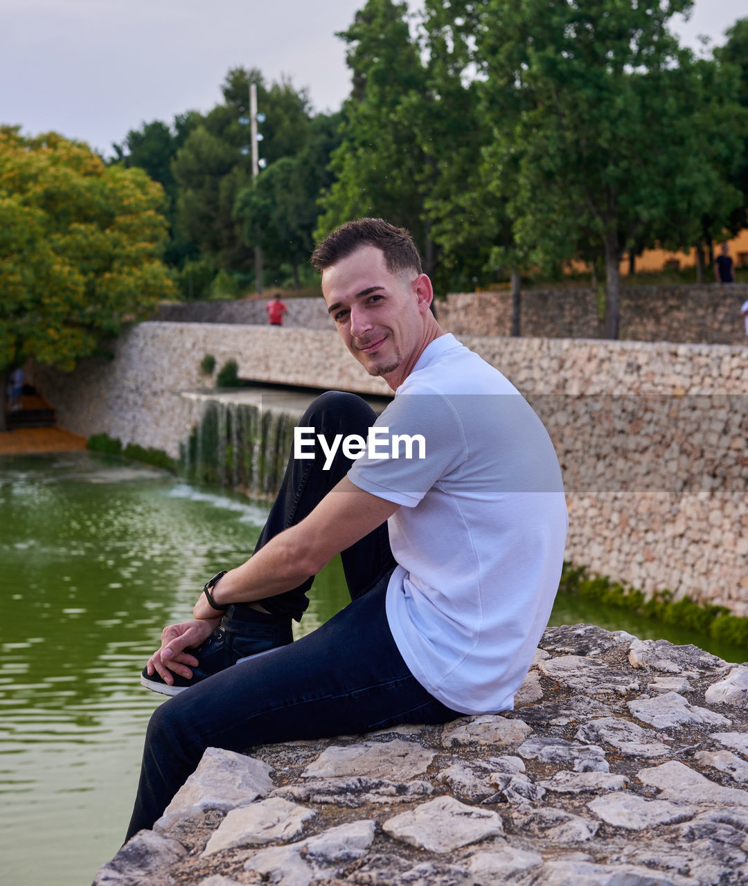 A young model seated on a wall in a park