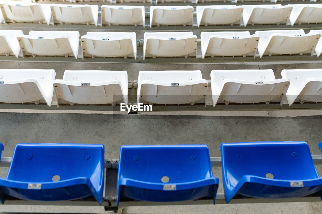 EMPTY CHAIRS AND TABLES IN ROW AGAINST BLUE WALL