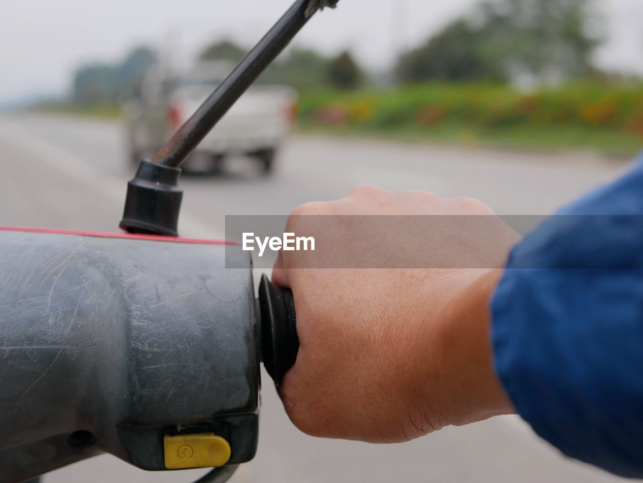 Cropped hand of man motor scooter on road