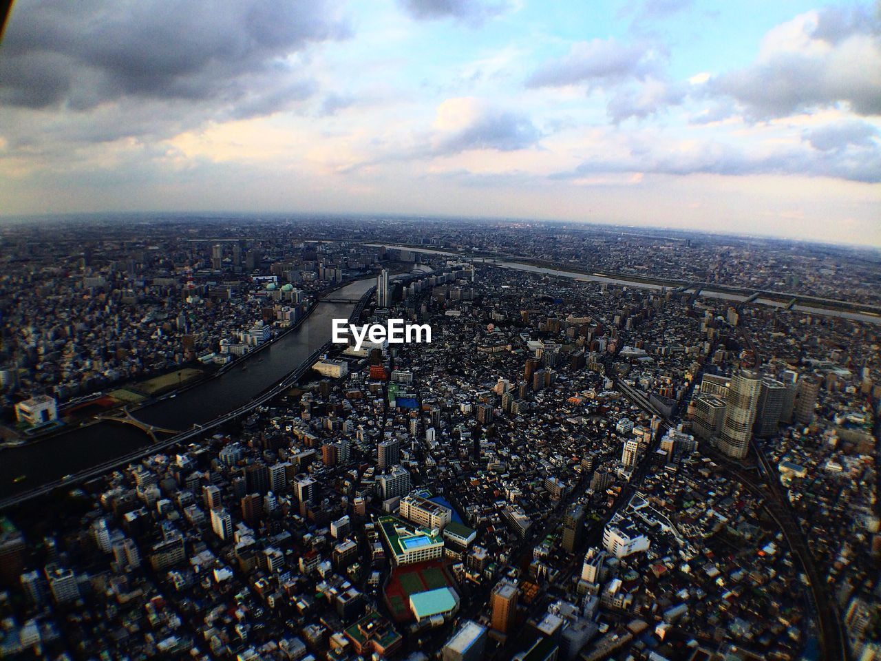 AERIAL VIEW OF CITYSCAPE AGAINST CLOUDY SKY