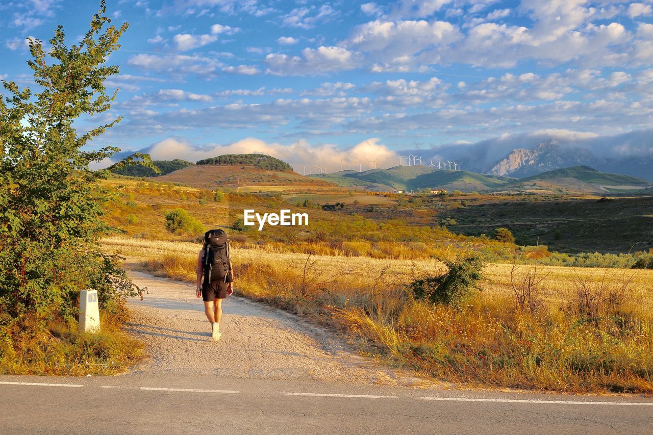 REAR VIEW OF WOMAN ON ROAD AGAINST MOUNTAIN