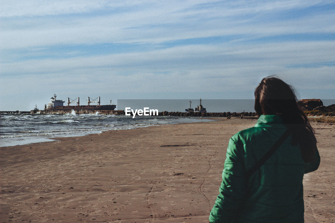 REAR VIEW OF WOMAN LOOKING AT SEA