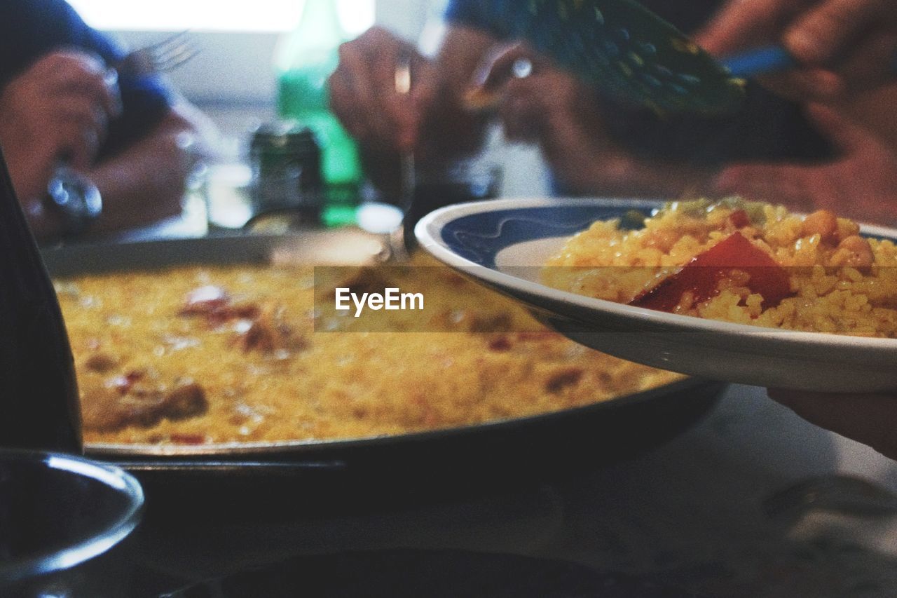 Cropped image of people enjoying paella in restaurant
