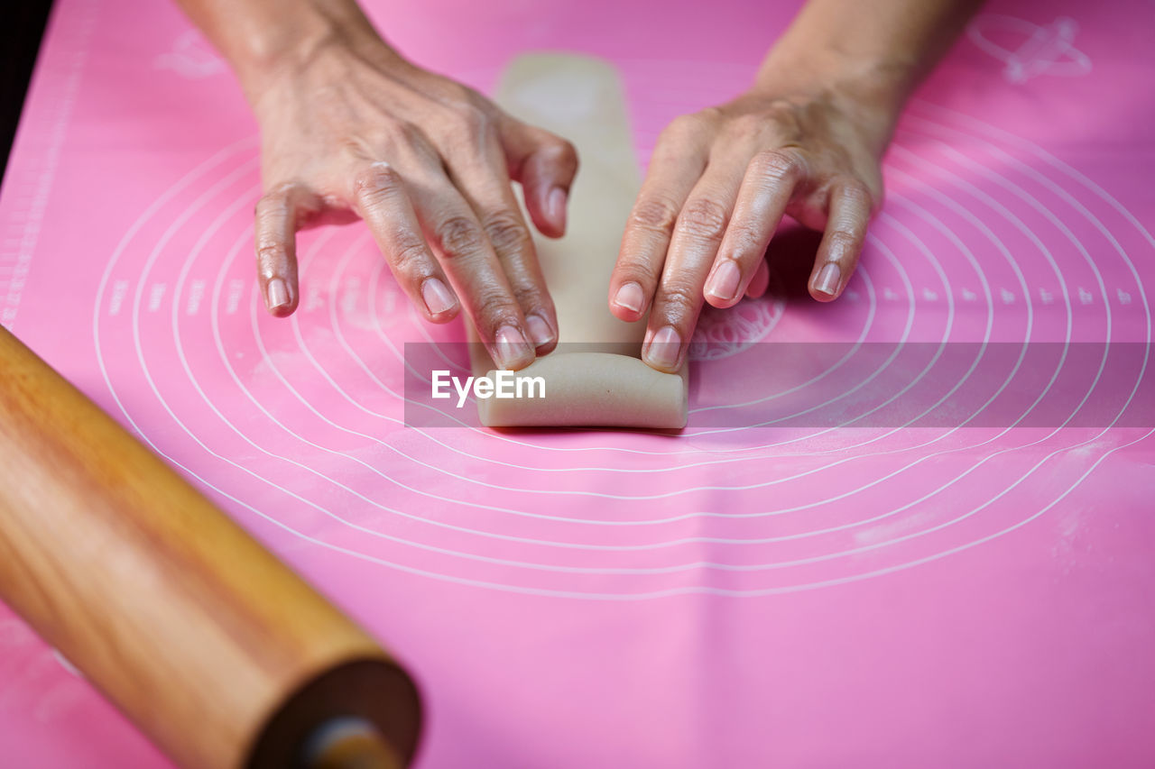 Woman's hands molding the rolle shape dough on pink silicone mesh