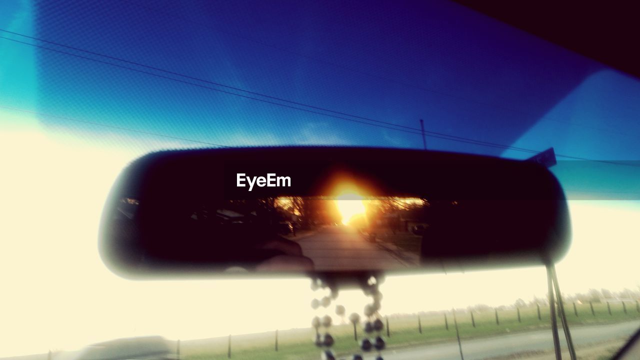 CLOSE-UP OF CAR ON SIDE-VIEW MIRROR AGAINST SKY