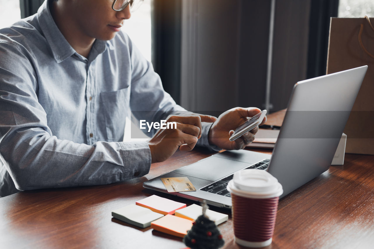 MIDSECTION OF MAN USING LAPTOP