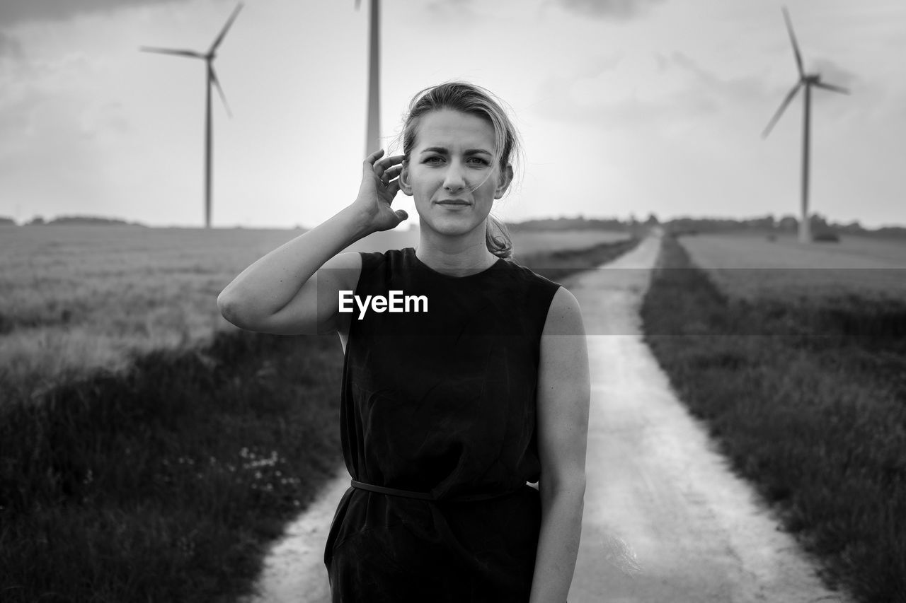 Portrait of beautiful young woman standing on country road