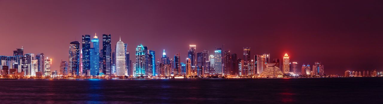 Illuminated buildings in city against sky at night