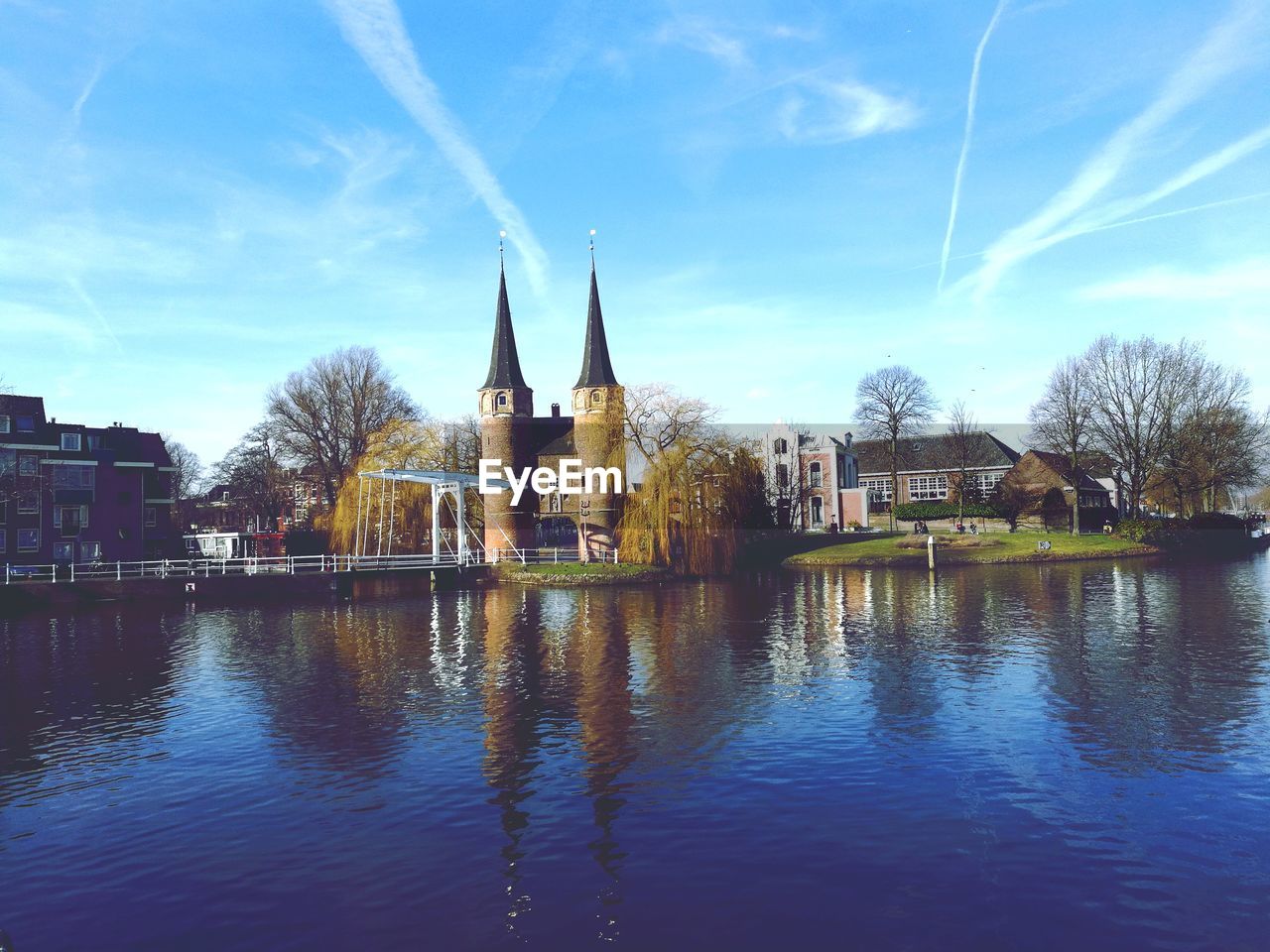 Buildings by river against blue sky
