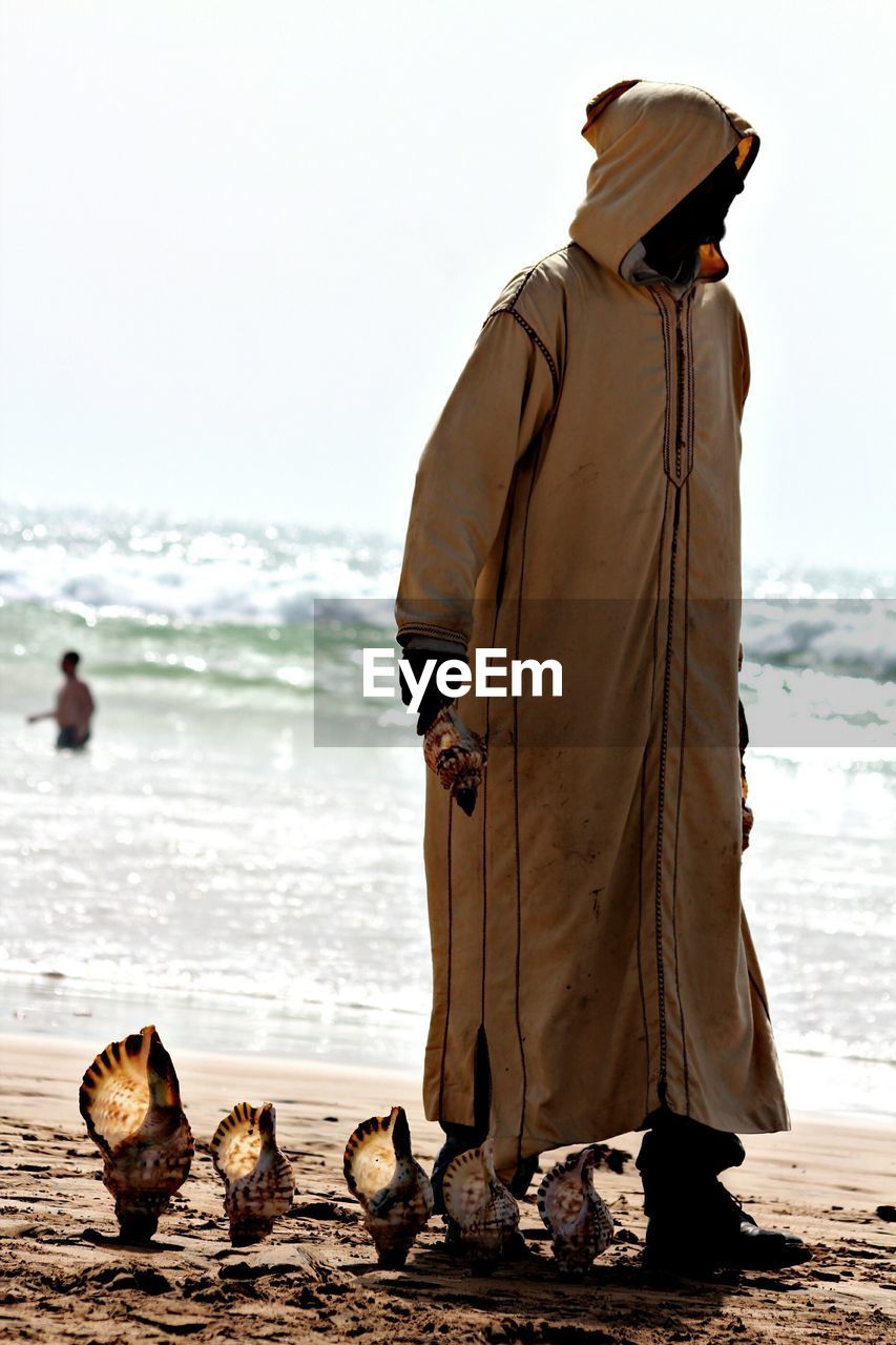 Full length of man with seashells standing at beach