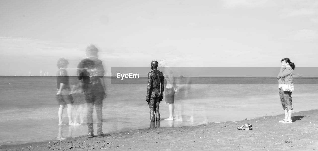 REAR VIEW OF MAN STANDING ON JETTY