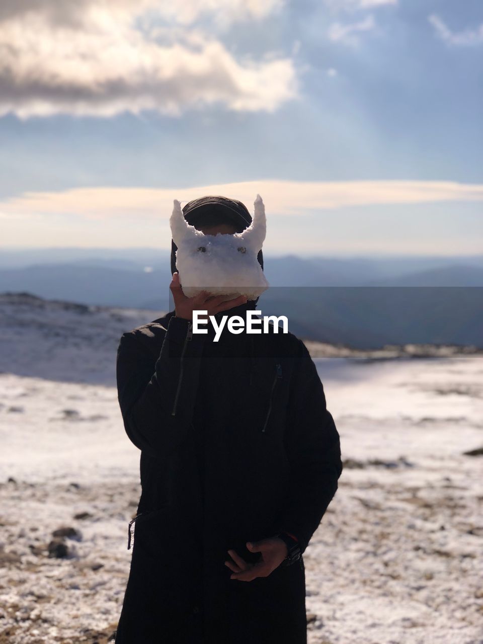 MAN WEARING MASK STANDING ON BEACH AGAINST SKY