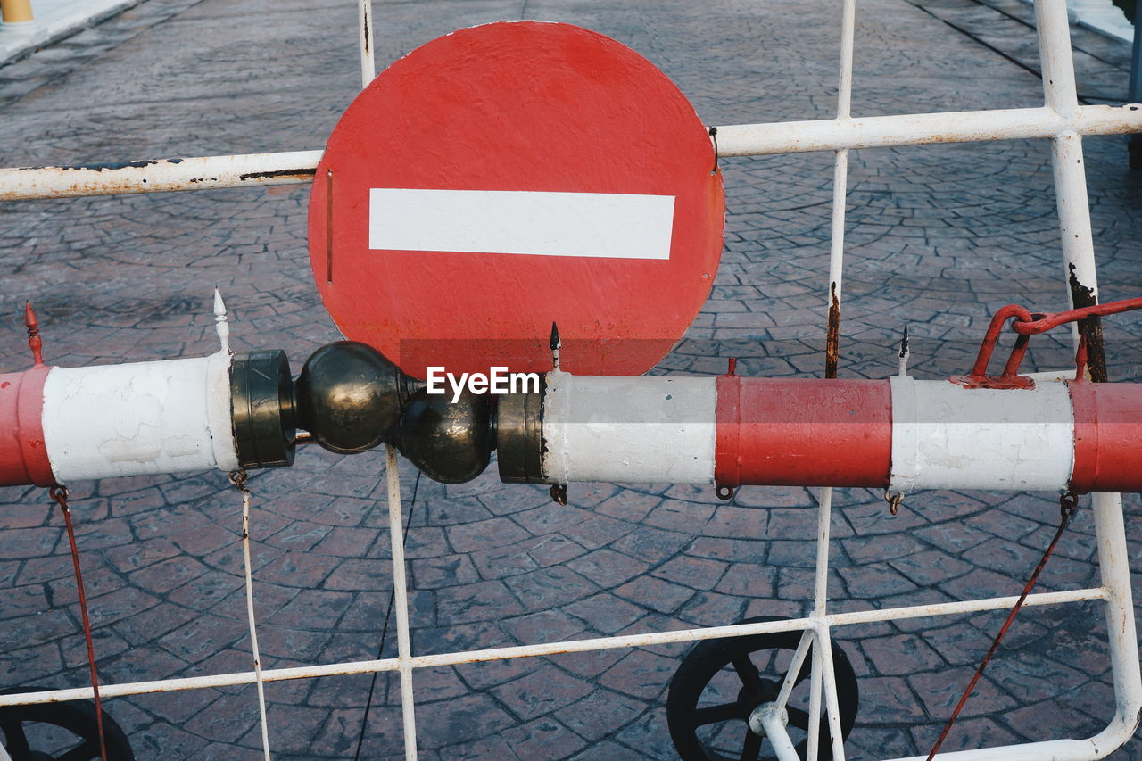 HIGH ANGLE VIEW OF ROAD SIGN BY FENCE