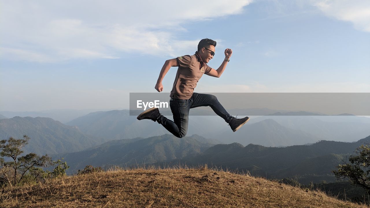 Full length of man jumping on mountains against sky