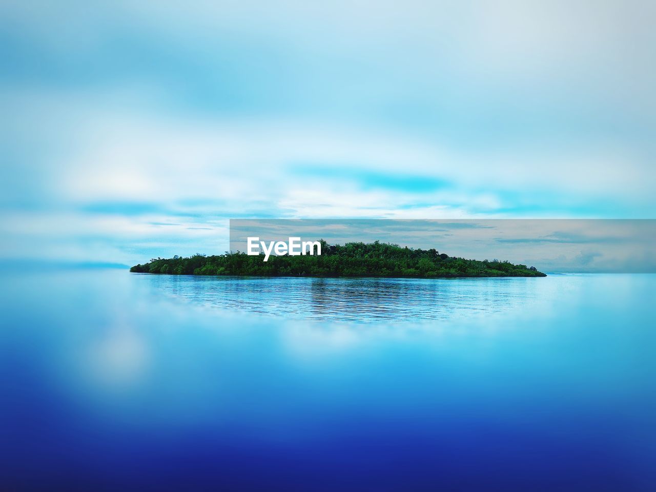 REFLECTION OF TREE IN SEA AGAINST SKY