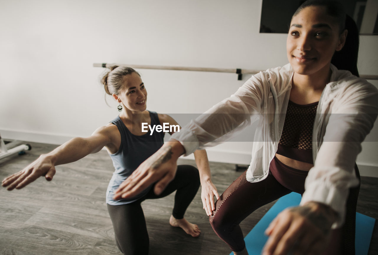 Female personal trainer coaches her female student how to squat