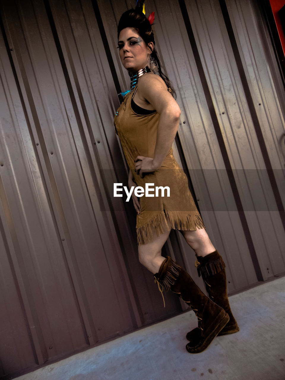 Portrait of young woman in costume posing by wall during halloween