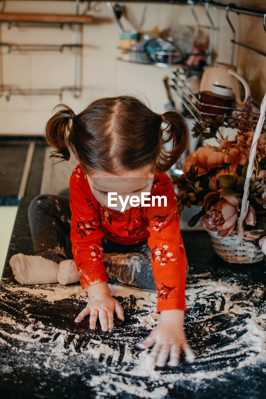 Full length of cute baby girl playing with flour on kitchen counter