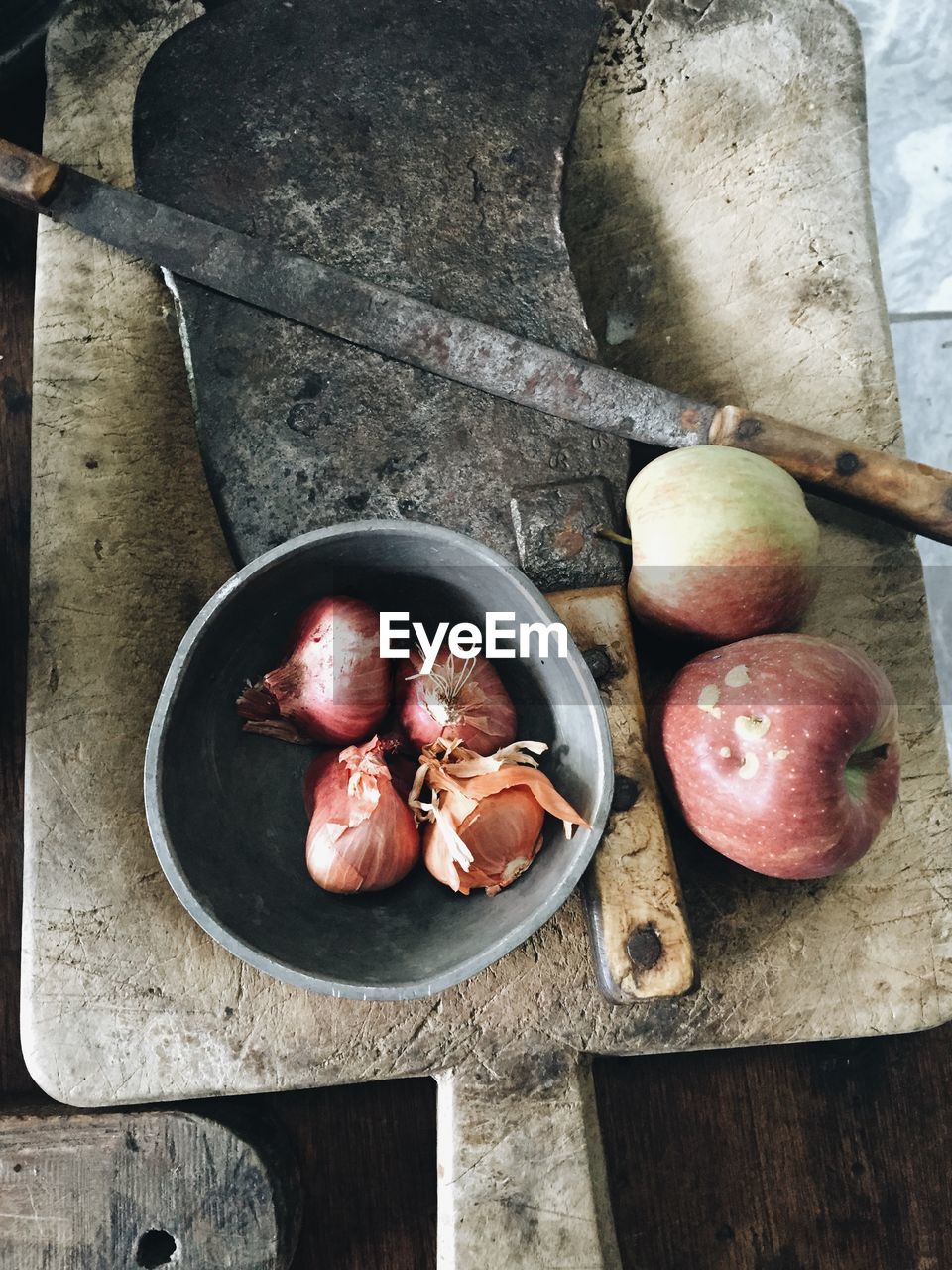 Directly above view of onions and apples with knife on cutting board