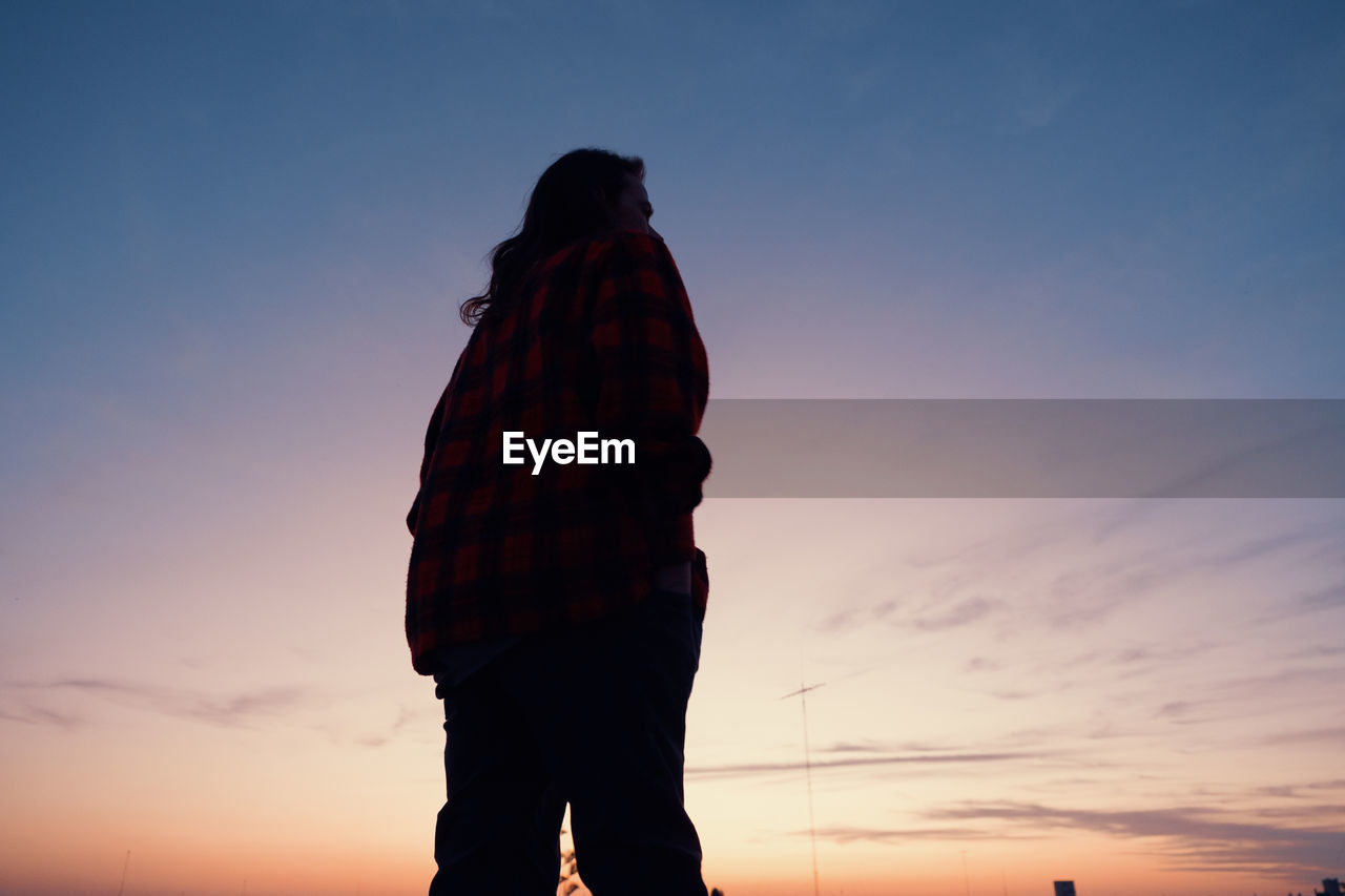 rear view of woman standing against clear sky during sunset