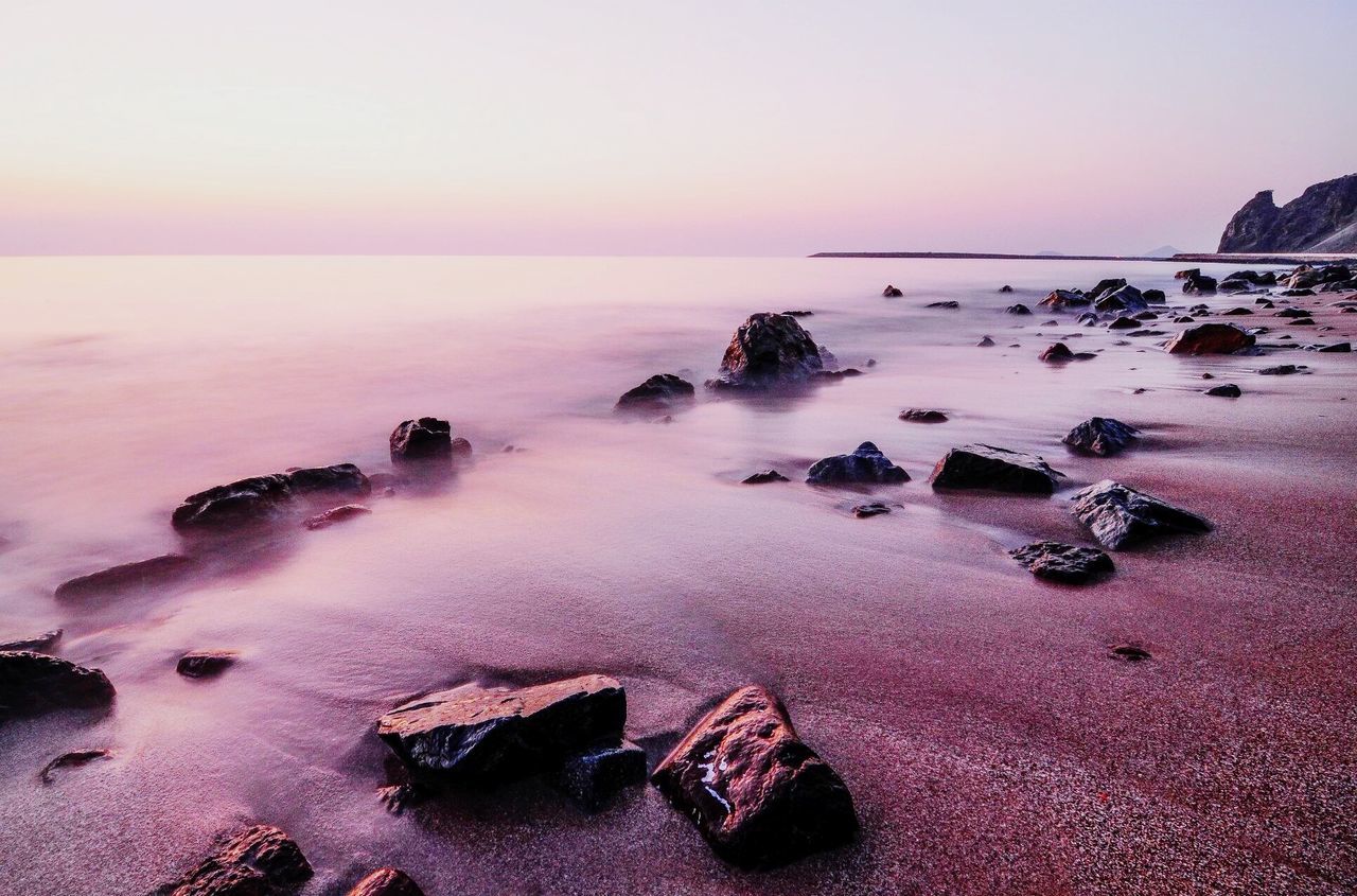 Rocks on shore at beach during sunset