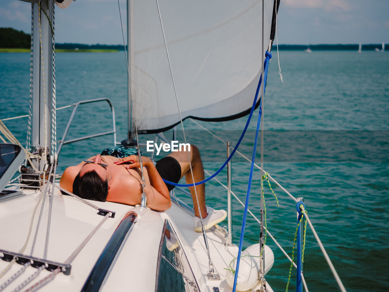 Young person sunbathing on a sailboat under the sail person