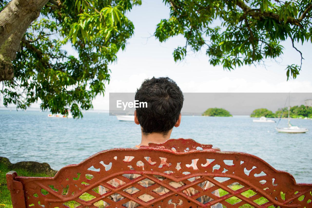 Rear view of man looking at sea against sky