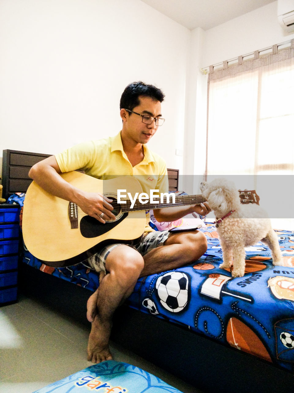 Man playing guitar with dog while sitting at home